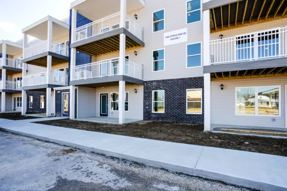 Cypress Point in Washington, Indiana: the three storey apartment building beside its front walk, with white balconies over a dark brick base and the building sign on the wall.